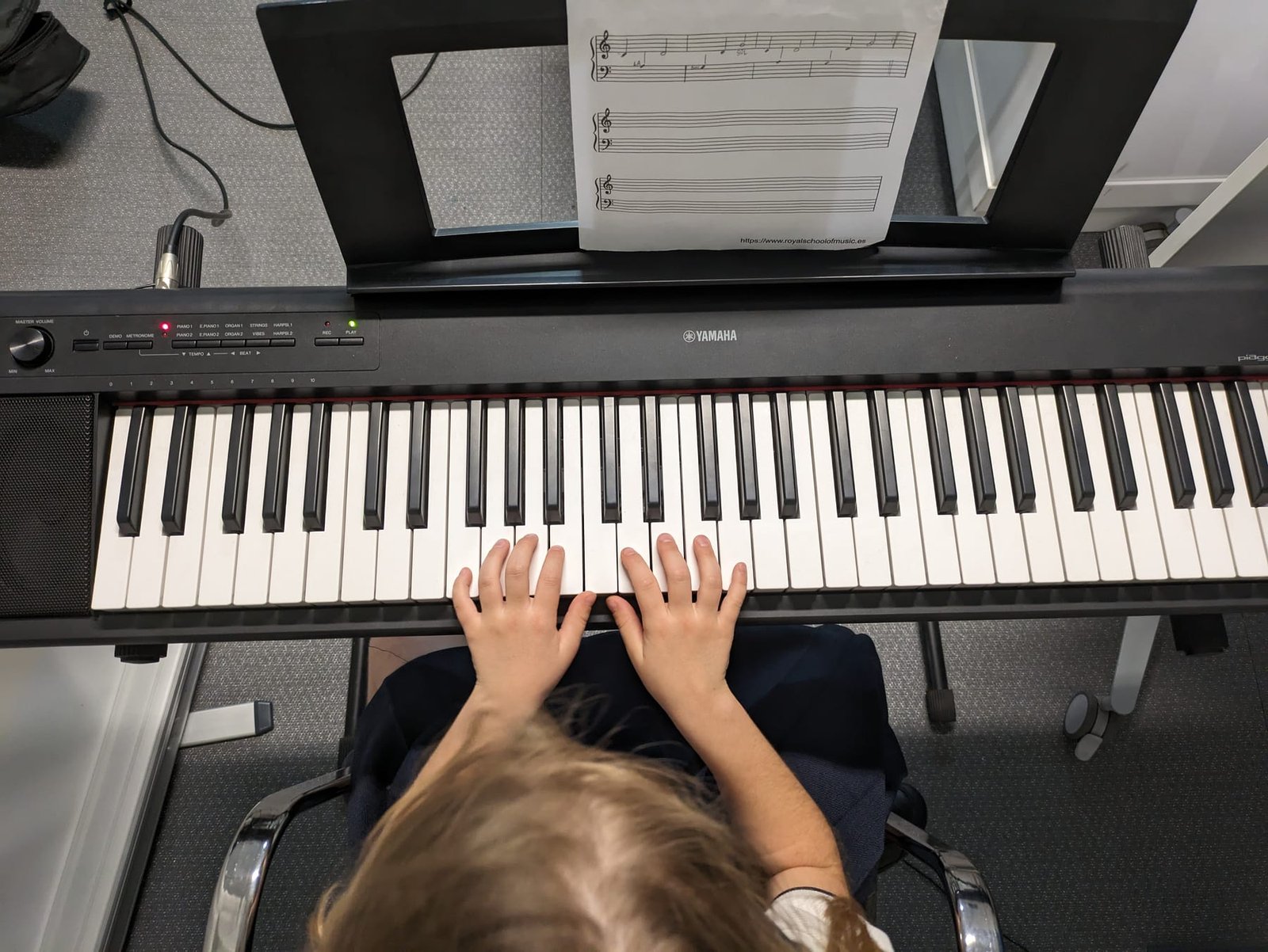 Manos de un alumno tocando el piano durante una clase de música en casa